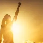 Femme levant le poing vers le ciel.